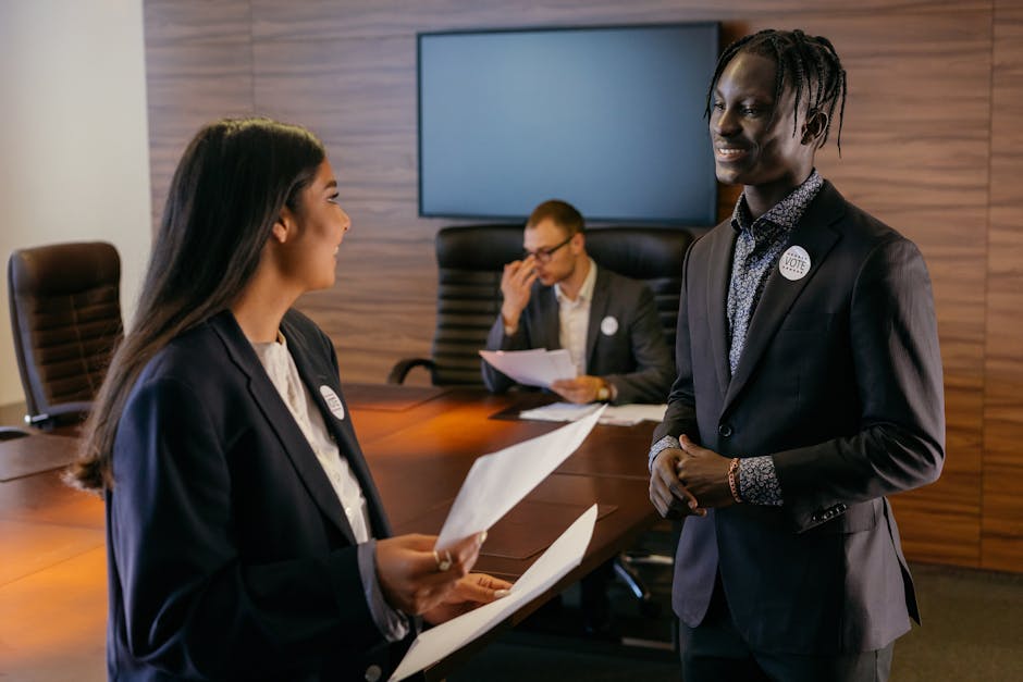 A diverse group of professionals engaged in conversation during a meeting in a modern conference room.